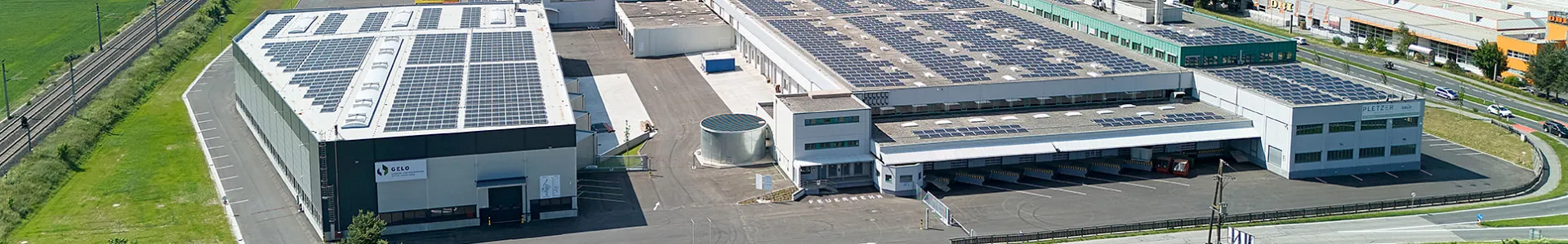 Luftaufnahme eines modernen Gewerbe- und Logistikstandorts der Pletzer Gruppe mit großflächigen Photovoltaikanlagen, Verladezonen und optimaler Verkehrsanbindung – exemplarisch für das Immobilienportfolio in Spittal und St. Pölten.